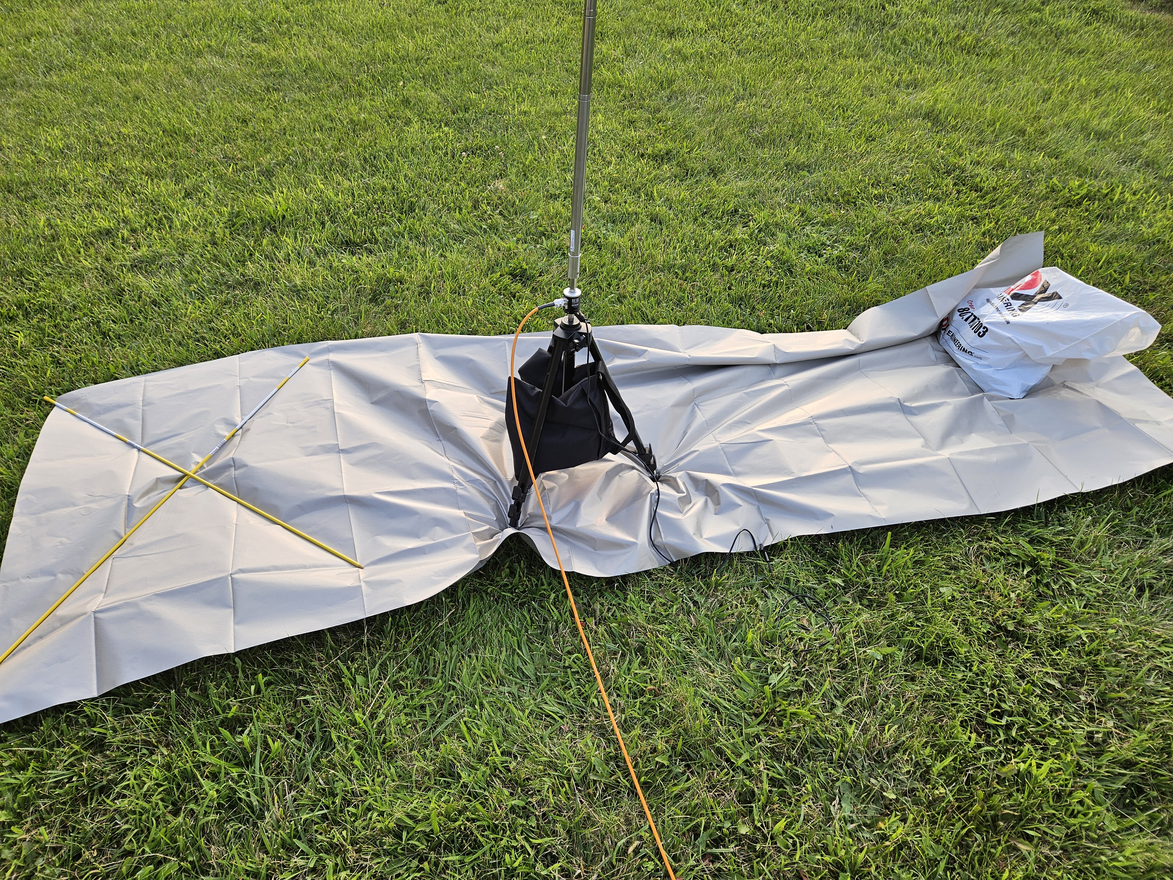 Vertical antenna on a camera tripod is set up atop faraday cloth with orange coaxial cable